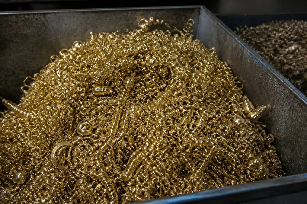 Brass turning swarf chips collected in machine shop bin ready for foundry re-melting credit